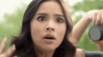 a woman with a surprised look on her face is holding a camera .