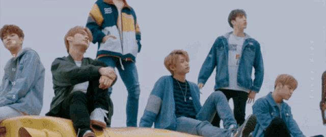 a group of young men are sitting on top of a yellow car and one of them is wearing a jacket that says nike