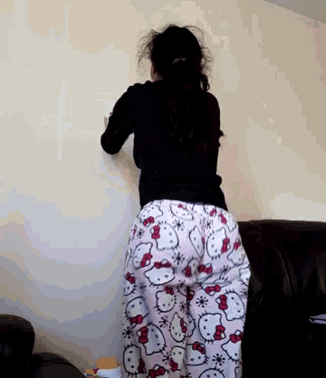 a woman wearing hello kitty pajamas is leaning against a white wall