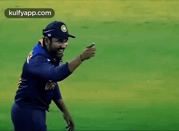 a cricket player is giving a thumbs up while standing on a green field .