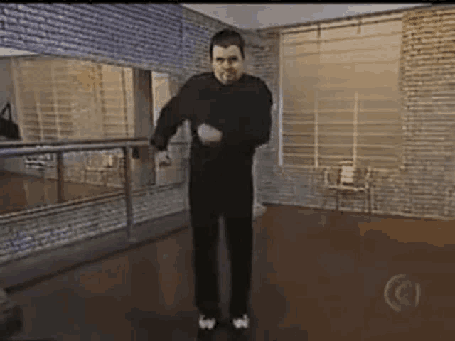 a man in a black sweater is dancing in a room