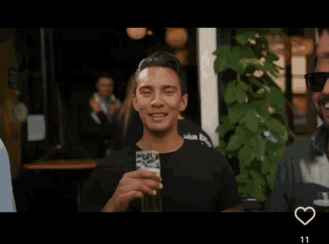 a man in a black shirt is drinking from a glass