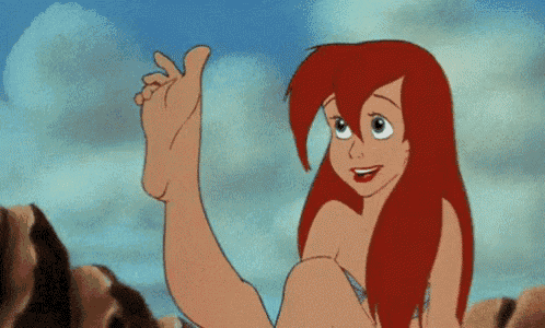 a cartoon character from the little mermaid is sitting on a rock and holding her foot up .