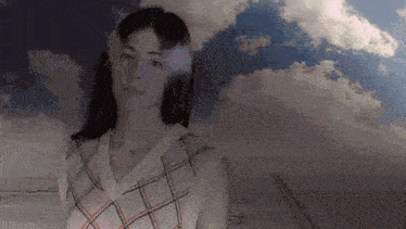 a woman is standing in front of a cloudy sky and looking at the camera .