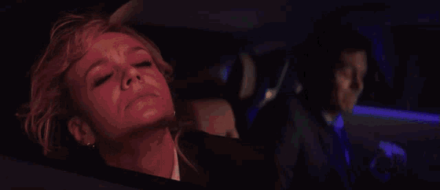 a woman is sleeping in the back seat of a car with her eyes closed