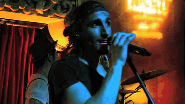 a man singing into a microphone in front of a sign that says lust