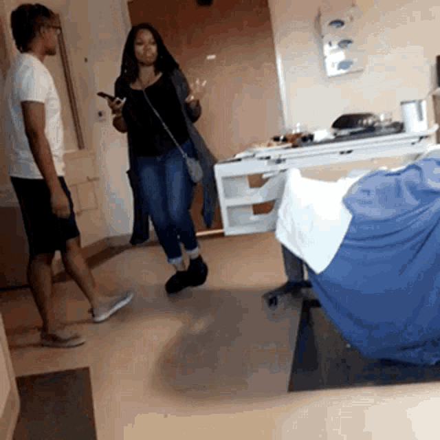 a man and a woman are standing in a hospital room near a bed