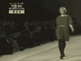 a woman is kneeling down on a runway in front of a crowd with the word collection on the bottom