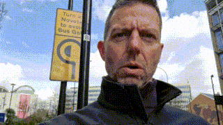 a man stands in front of a yellow sign that says turn a narrow to avoid bus gap