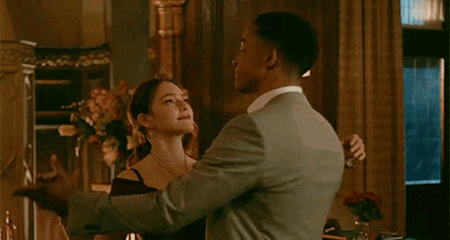 a man in a suit and a woman in a dress are dancing together in a room .