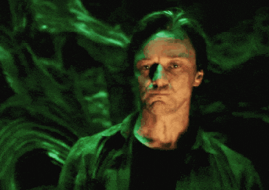 a man in a green shirt is standing in a dark room