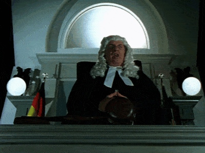 a man in a wig is holding a judge 's gavel in front of a window
