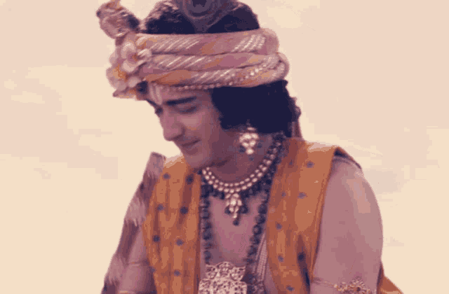 a man wearing a turban and a peacock feather on his head holds a flute
