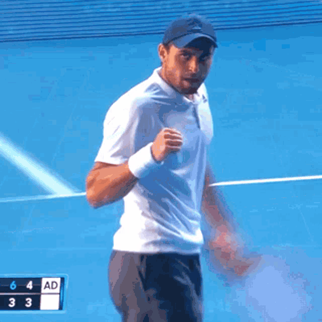 a man in a white shirt is on a tennis court with a scoreboard behind him that says 6 4 ad 33