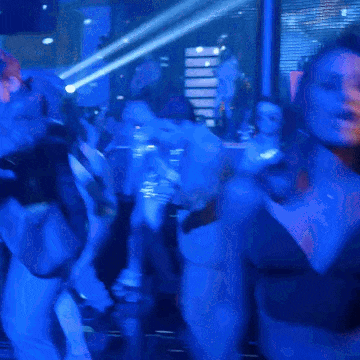 a woman in a black top is dancing in a crowded room