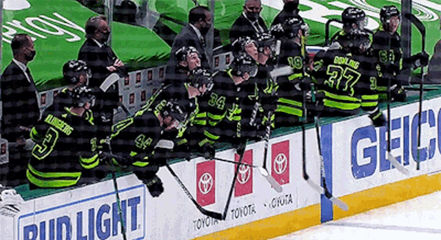 a group of hockey players are sitting on a bench with a bud light sign in the background