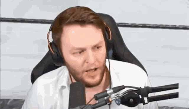 a man wearing headphones is sitting in front of a microphone .