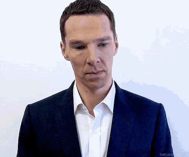 a man wearing a suit and white shirt is looking down