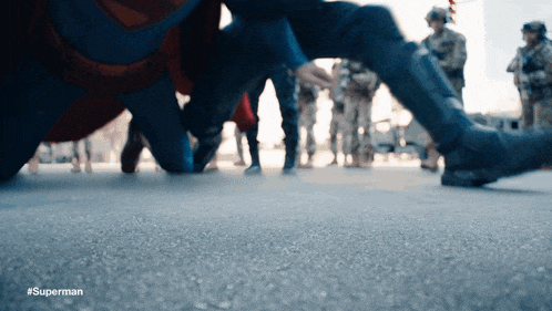 a person in a superman costume is kneeling down in front of a crowd of people