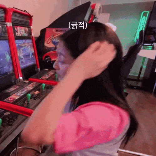 a woman adjusts her hair in front of an arcade machine that has the word midway on it