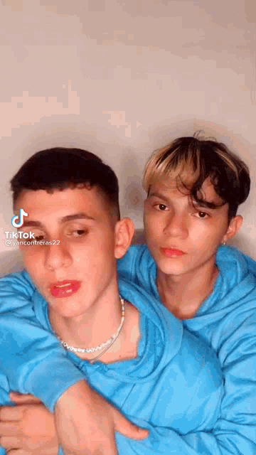 two young men in blue sweatshirts are hugging each other