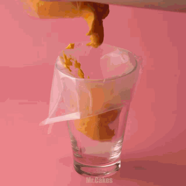 a glass filled with yellow frosting is being poured into a piping bag