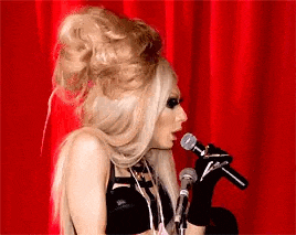 a woman in a wig is singing into a microphone .