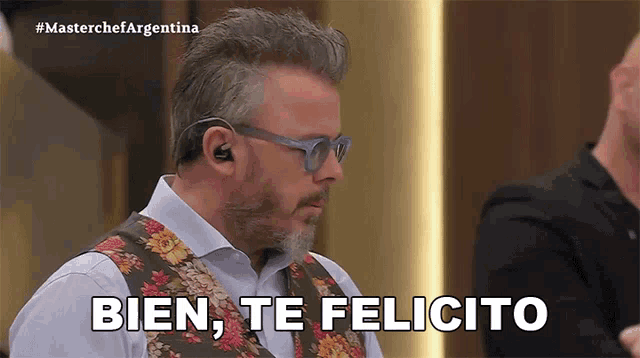a man wearing glasses and a vest says bien te felicita