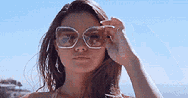 a woman in a bikini is wearing sunglasses and looking through them .