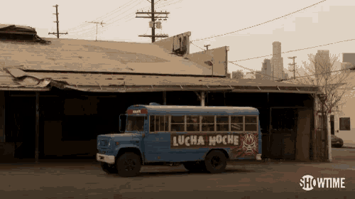 a blue bus with lucha noche written on the side is parked in front of a building