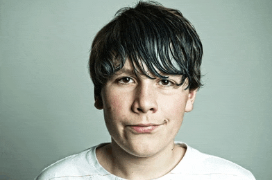 a young boy making a funny face with a white shirt on
