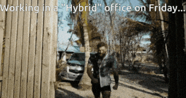 a man standing in front of a wooden fence with the words working in a hybrid office on friday