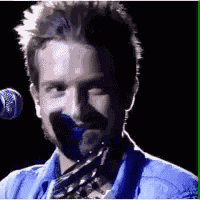 a man is singing into a microphone while holding a guitar