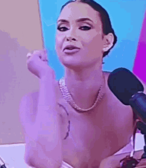 a woman is talking into a microphone while wearing a pearl necklace and earrings .