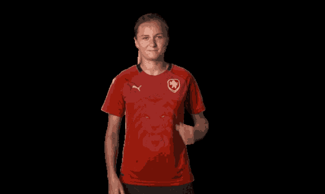 a woman in a red shirt with a lion on it is giving a thumbs up