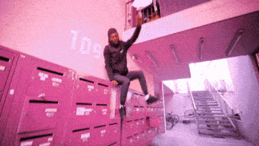 a man is jumping over a pink locker with the number 109 on the wall behind him