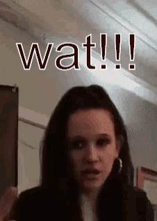 a woman with dark hair says wat !!! in front of her