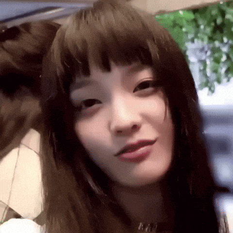 a close up of a woman 's face with long dark hair and bangs .