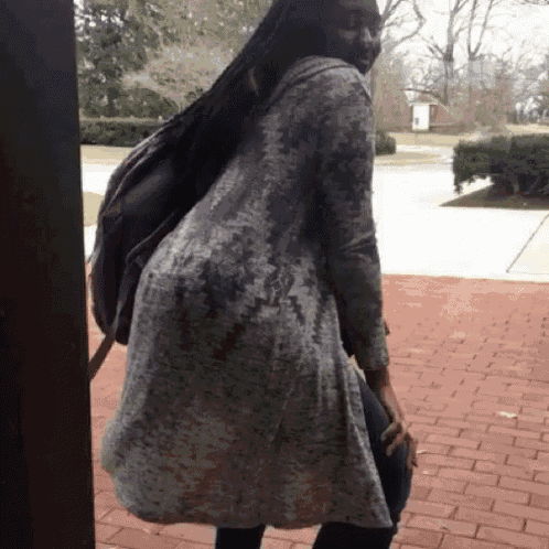a woman standing on a brick sidewalk with a backpack on her back ..