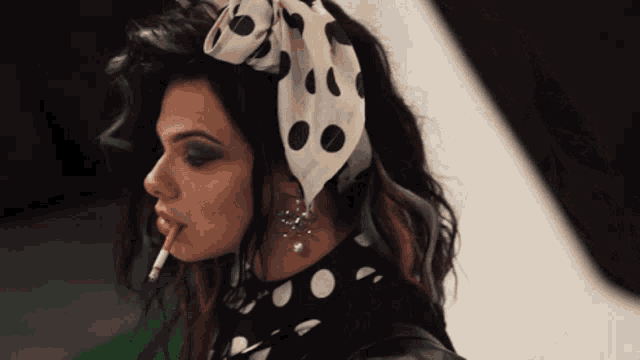 a woman smoking a cigarette with a polka dot headband