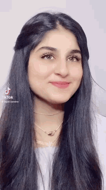 a woman with long black hair is smiling and wearing a necklace with the name sandra on it