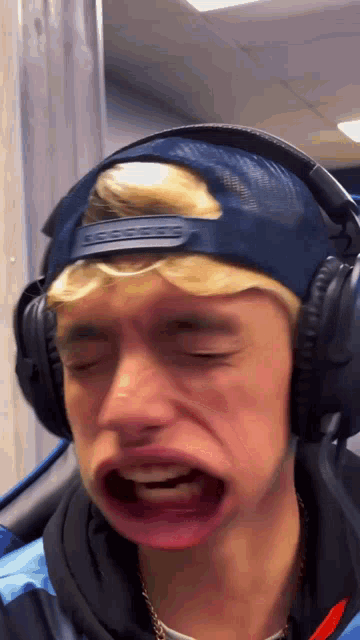 a man wearing headphones and a blue hat making a funny face