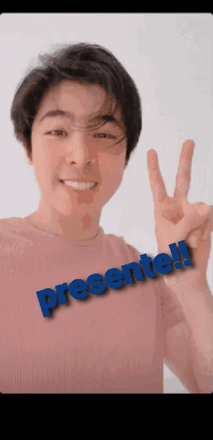 a man in a pink shirt giving a peace sign