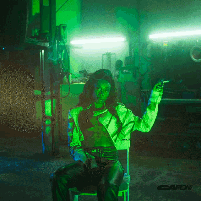 a woman in a green jacket is sitting in a chair with the word gafoni on the bottom