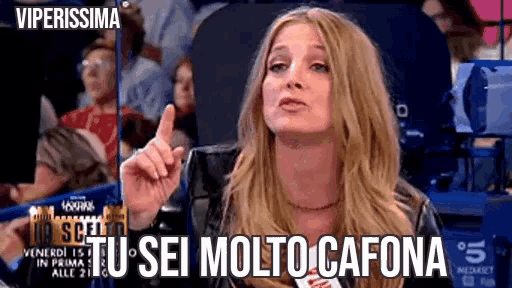 a woman in a black jacket is giving a speech in front of a crowd and says " tu sei molto cafona "