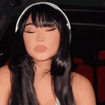 a woman with long black hair and bangs is wearing headphones .