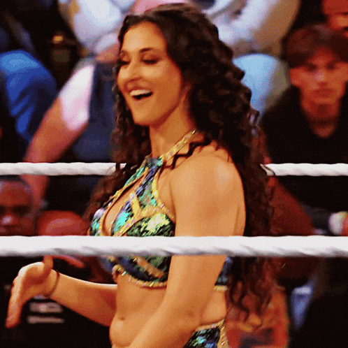 a woman in a bikini is standing in a wrestling ring smiling