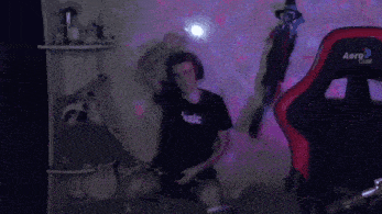 a man wearing a black shirt that says basic is dancing in a dark room