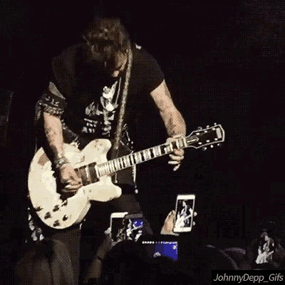 a man playing a guitar on a stage with a watermark that says johnny depp_gifs