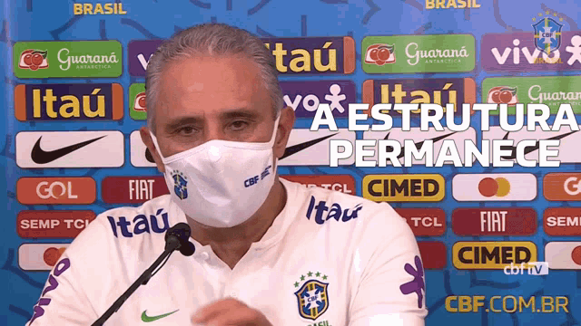 a man wearing a face mask is talking into a microphone in front of a banner that says brasil